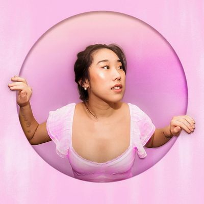Portrait of a smiling woman, Iryna, with a calm expression against a pink circle.